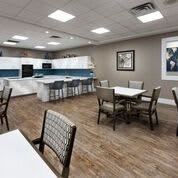 A modern kitchen and dining area with several tables and chairs, featuring bright lighting and contemporary interior design.