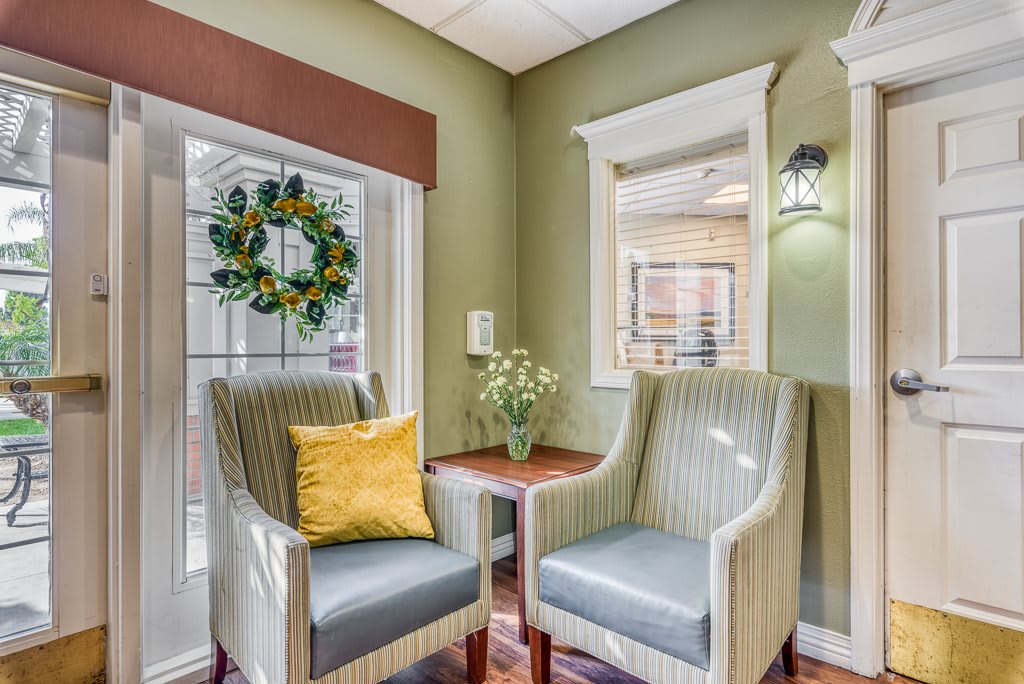 A cozy living room corner with two armchairs and a decorative wreath on the window.