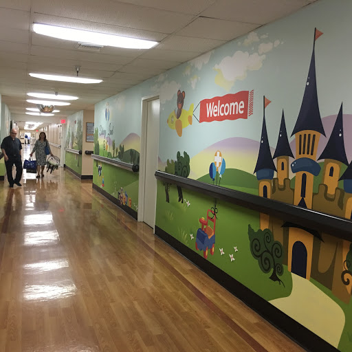 A colorful hallway decorated with a welcoming mural featuring castles and playful scenes, designed to create a friendly atmosphere.