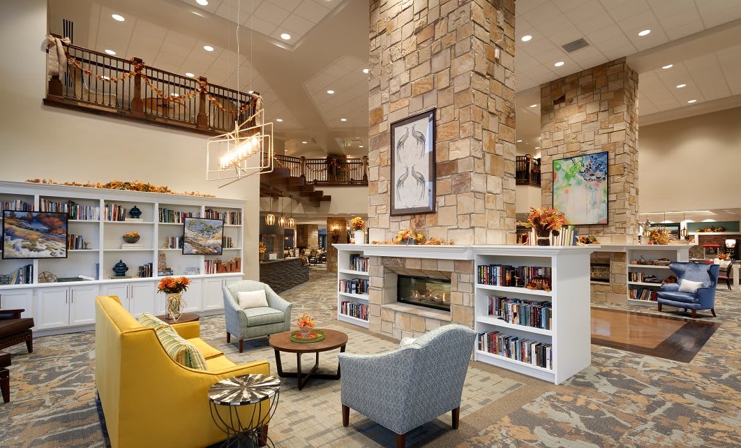 A modern lobby with a cozy seating area featuring a stone fireplace and bookshelves.