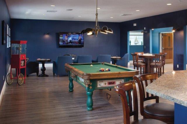 A modern billiard room with a pool table, television, and lounge seating.
