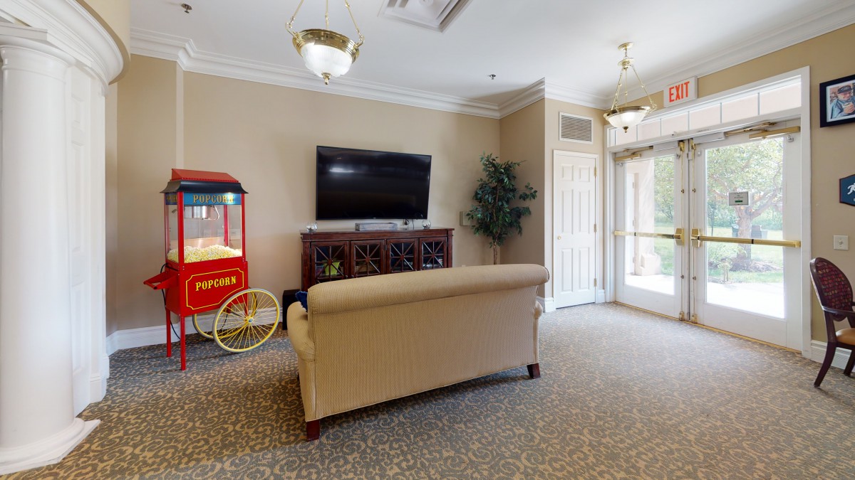 A cozy living room featuring a sofa facing a mounted television and a vintage popcorn machine.