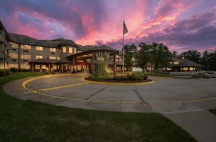 A beautifully lit building at sunset with a dramatic sky and flagpole in the foreground.