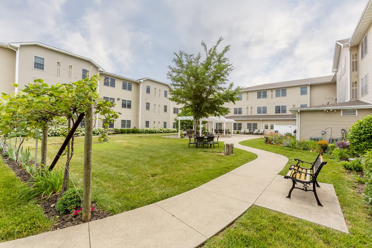A residential building with a landscaped courtyard featuring a pathway, benches, and greenery.