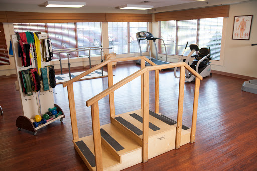 A rehabilitation gym featuring a wooden stair setup, designed for physical therapy and exercise.