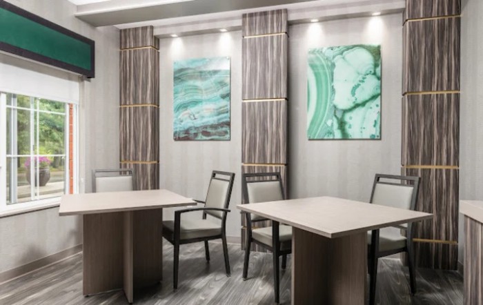 A modern conference room with tables, chairs, and abstract artwork on the walls.