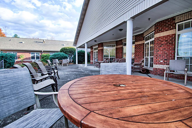 A spacious outdoor patio with tables and chairs next to a brick building with large windows.