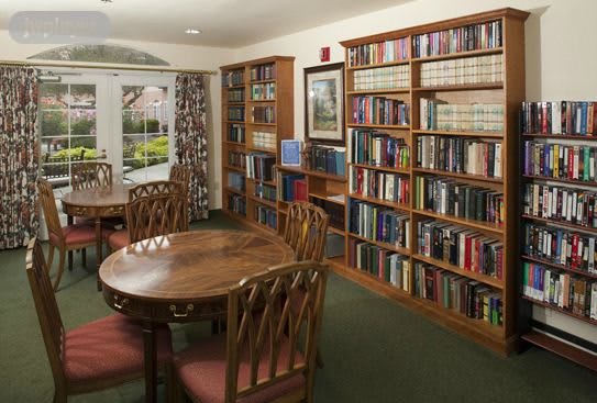 A cozy library room with bookshelves, a wooden table, and chairs.