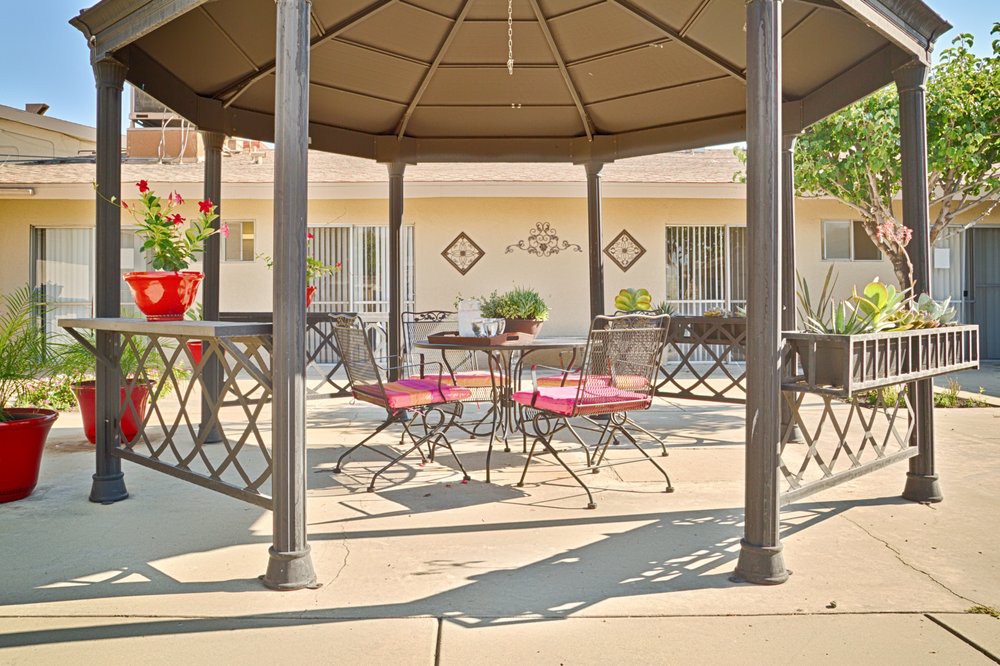 A cozy outdoor gazebo with metal furniture on a sunny patio.