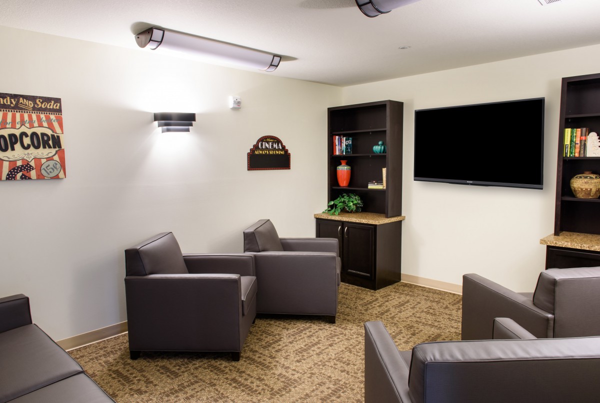A modern lounge area featuring comfortable chairs, a television, and a bookshelf.