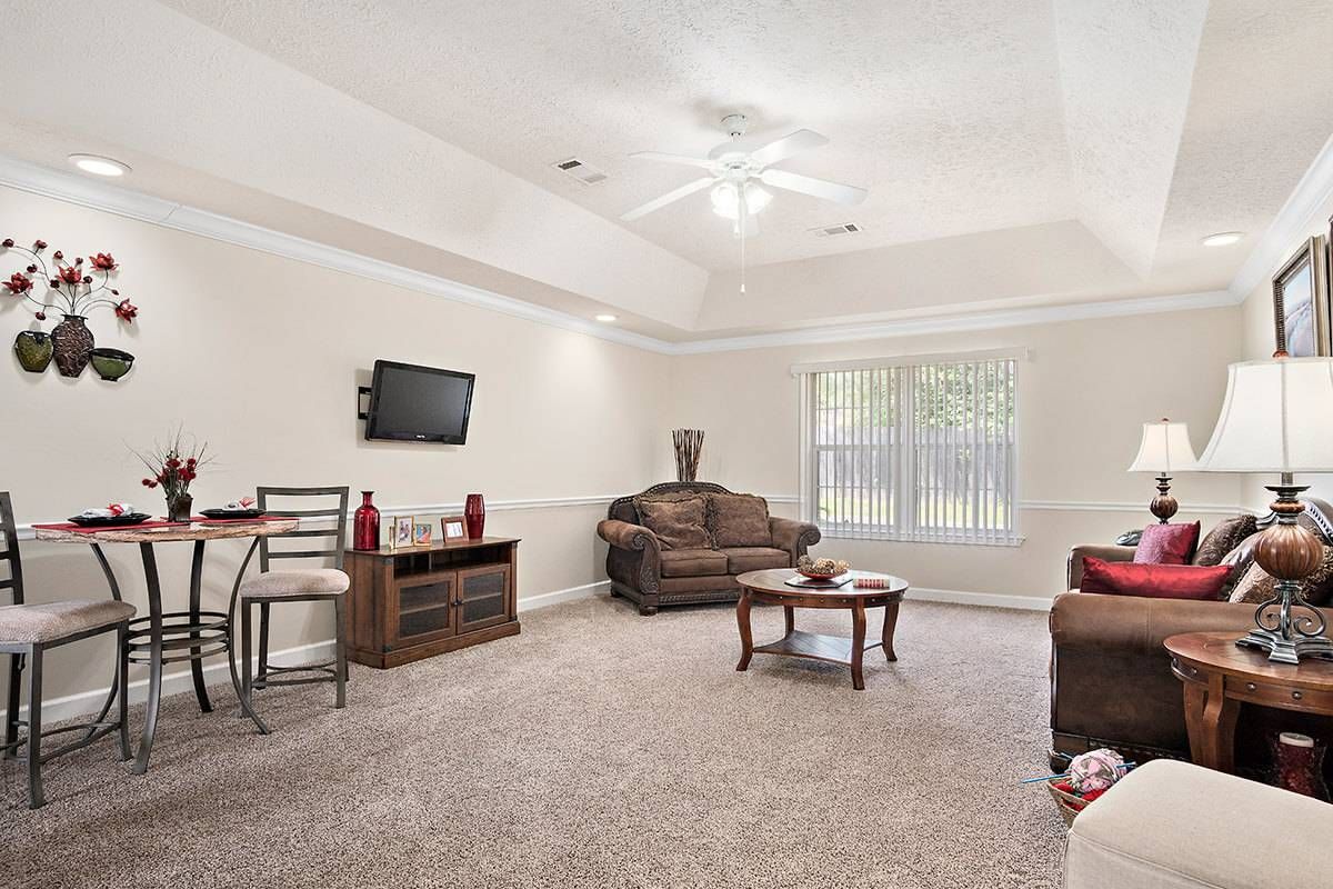 A cozy living room featuring comfortable seating, a mounted television, and a large window with natural light.