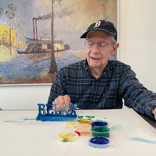 An elderly man engages in a creative activity with painting supplies, showcasing a moment of artistic expression.