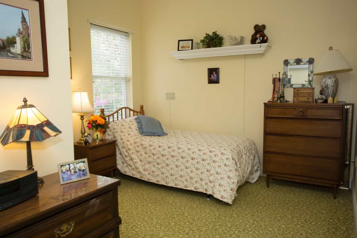 A cozy bedroom with a single bed, dresser, and decorative shelf.