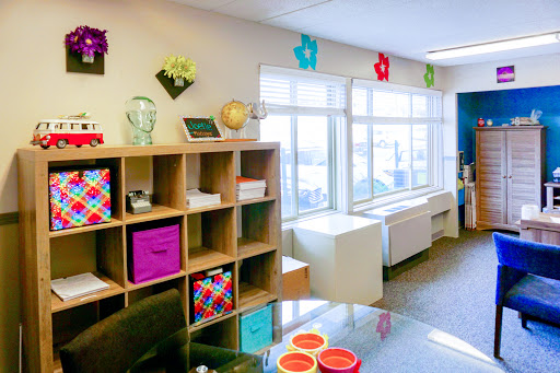 A bright and colorful office space featuring organized shelves and large windows allowing natural light.