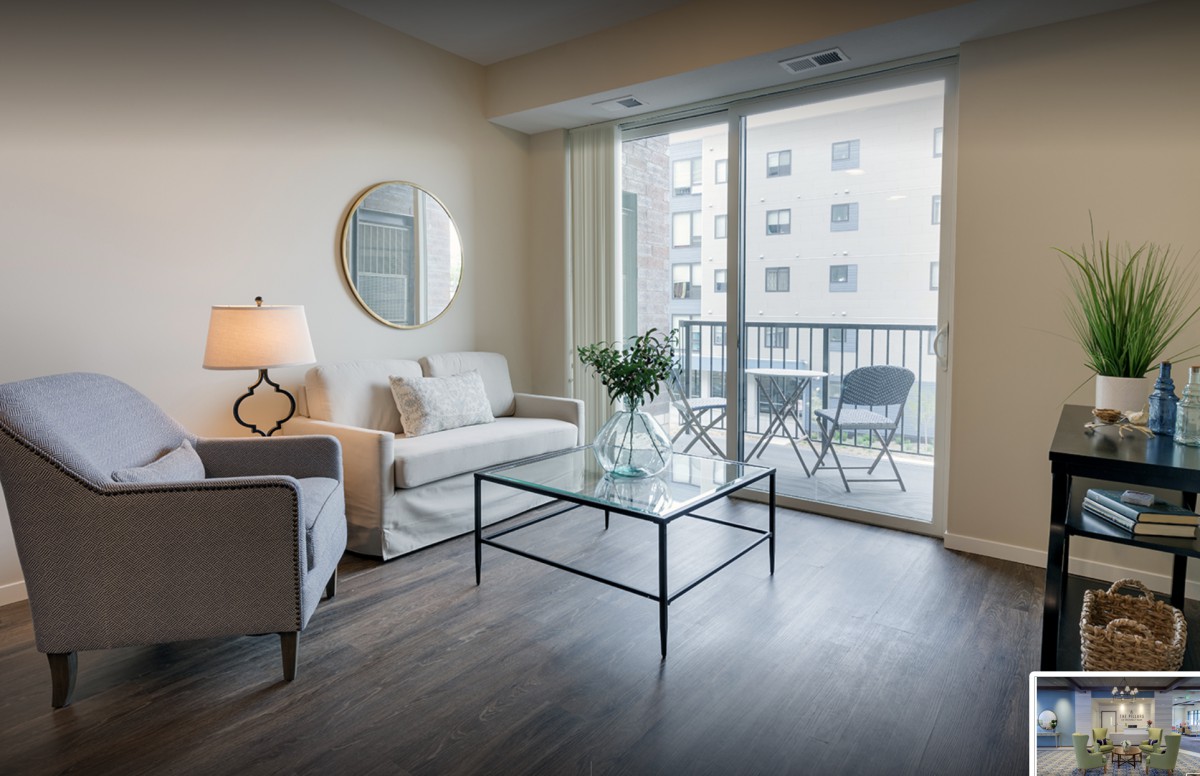A modern living room with a sofa, glass coffee table, and a view of the balcony.
