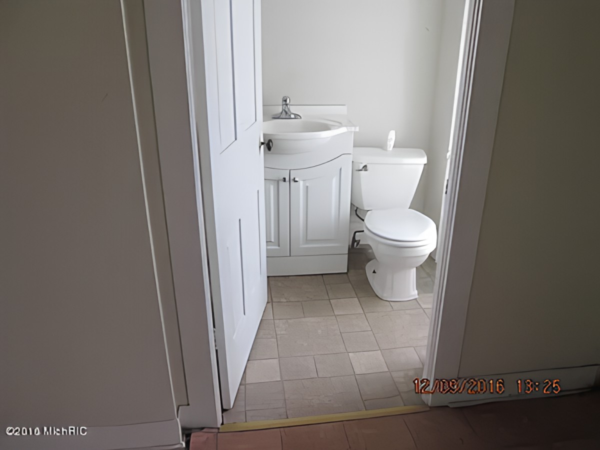 A small bathroom with a toilet and sink, featuring white walls and a minimalist design.