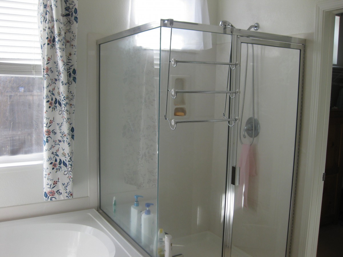 A clean bathroom featuring a glass shower enclosure and a bathtub with a curtain.