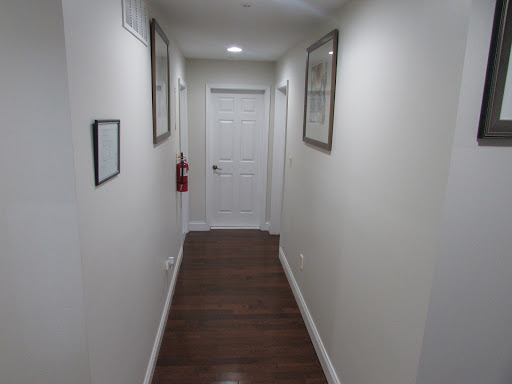 A well-lit hallway featuring framed pictures on the walls, leading to a closed door.