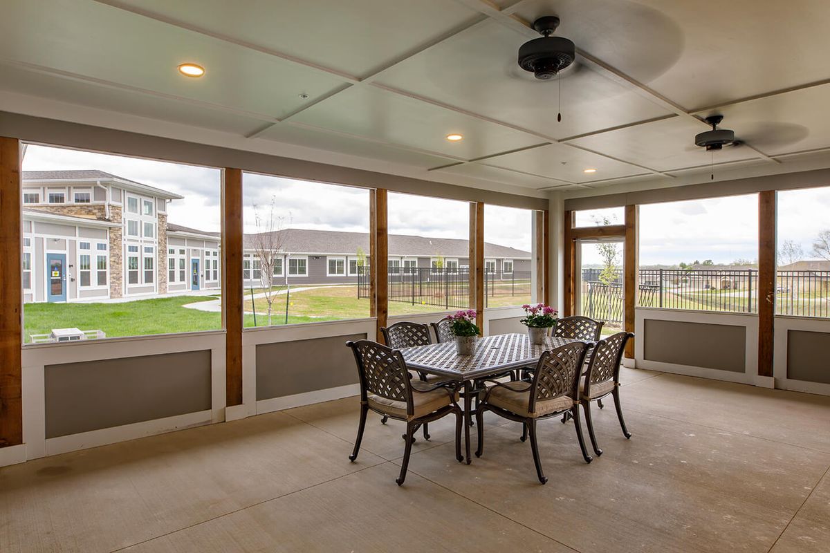 A spacious sunroom featuring a dining table with chairs, surrounded by large windows offering an outdoor view.