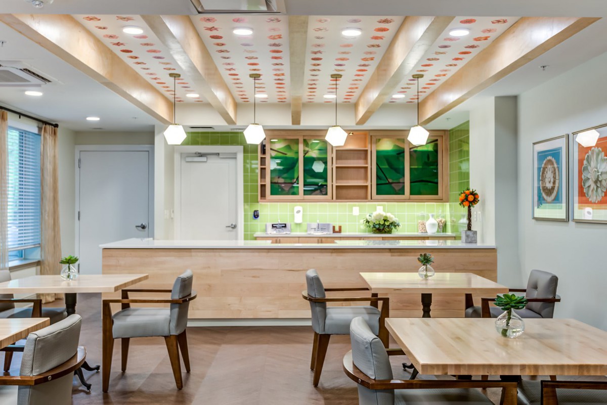 A modern restaurant interior featuring wooden tables, stylish chairs, and a bright, inviting atmosphere with green accent walls.