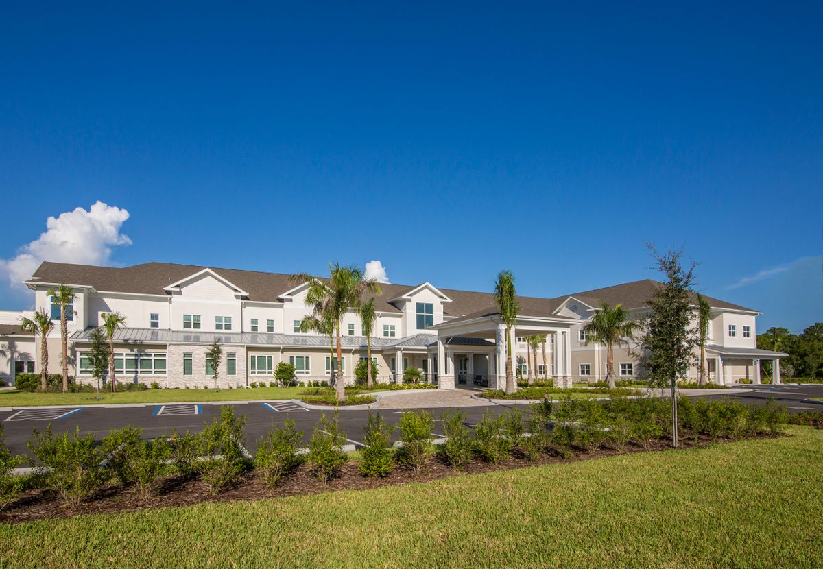 A modern residential building surrounded by greenery under a clear blue sky.