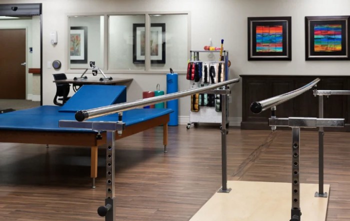 A physical therapy clinic with parallel bars and various equipment.