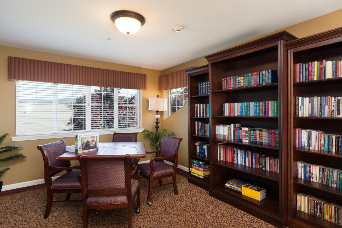 Cozy reading room with a table, chairs, and a well-stocked bookshelf.