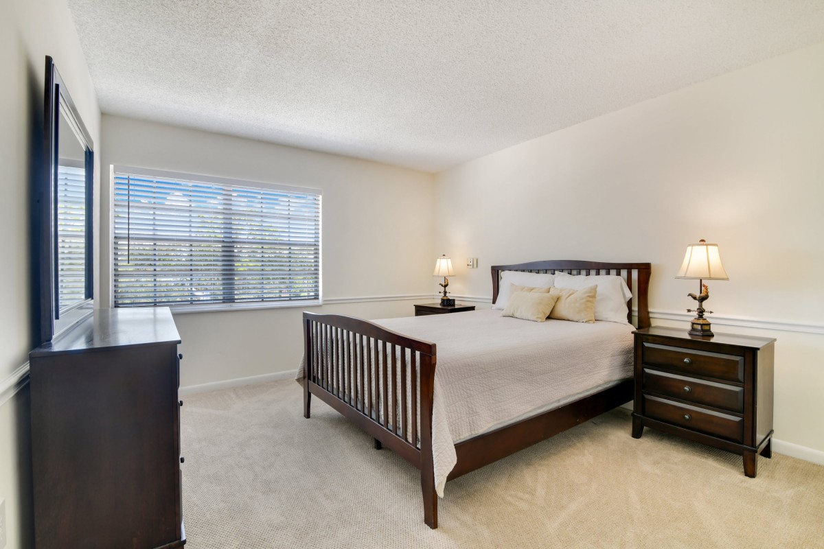 A bright and cozy bedroom with a wooden bed frame, dresser, and nightstands.