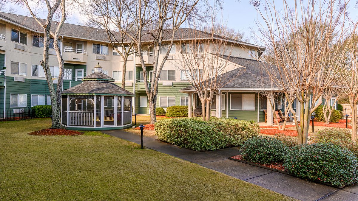 A well-maintained building with a gazebo surrounded by trees and landscaped gardens.