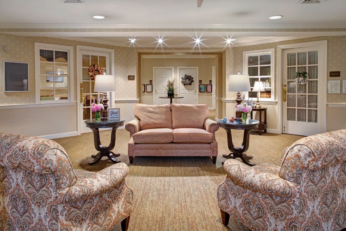 A cozy lobby area featuring a sofa, armchairs, and lamps with elegant decor.