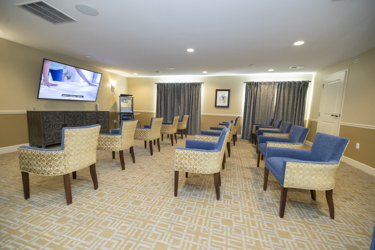 A spacious waiting room with multiple chairs, a television, and carpeted flooring.