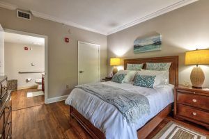A cozy bedroom with a neatly made bed, stylish pillows, and a warm lamp.