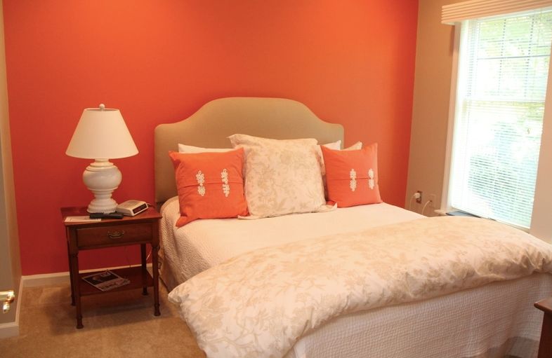 A cozy bedroom with vibrant orange walls and a neatly made bed.