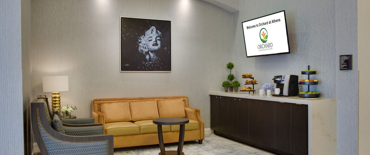 A modern lobby area with a comfortable sofa, stylish artwork, and a television screen, creating an inviting atmosphere.