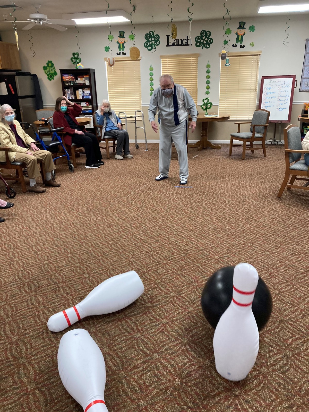 Seniors enjoying a game of indoor bowling in a community center.