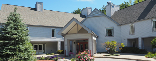 A welcoming entrance to a beautifully designed building surrounded by vibrant flowers.