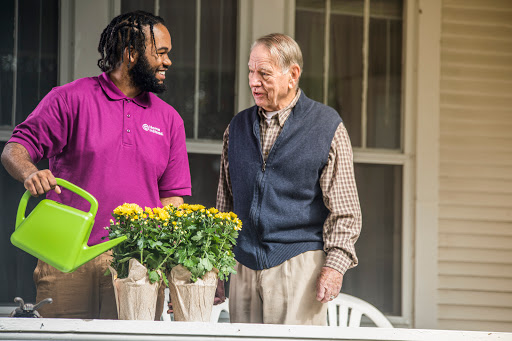 A warm interaction between two individuals tending to flowers on a porch.
