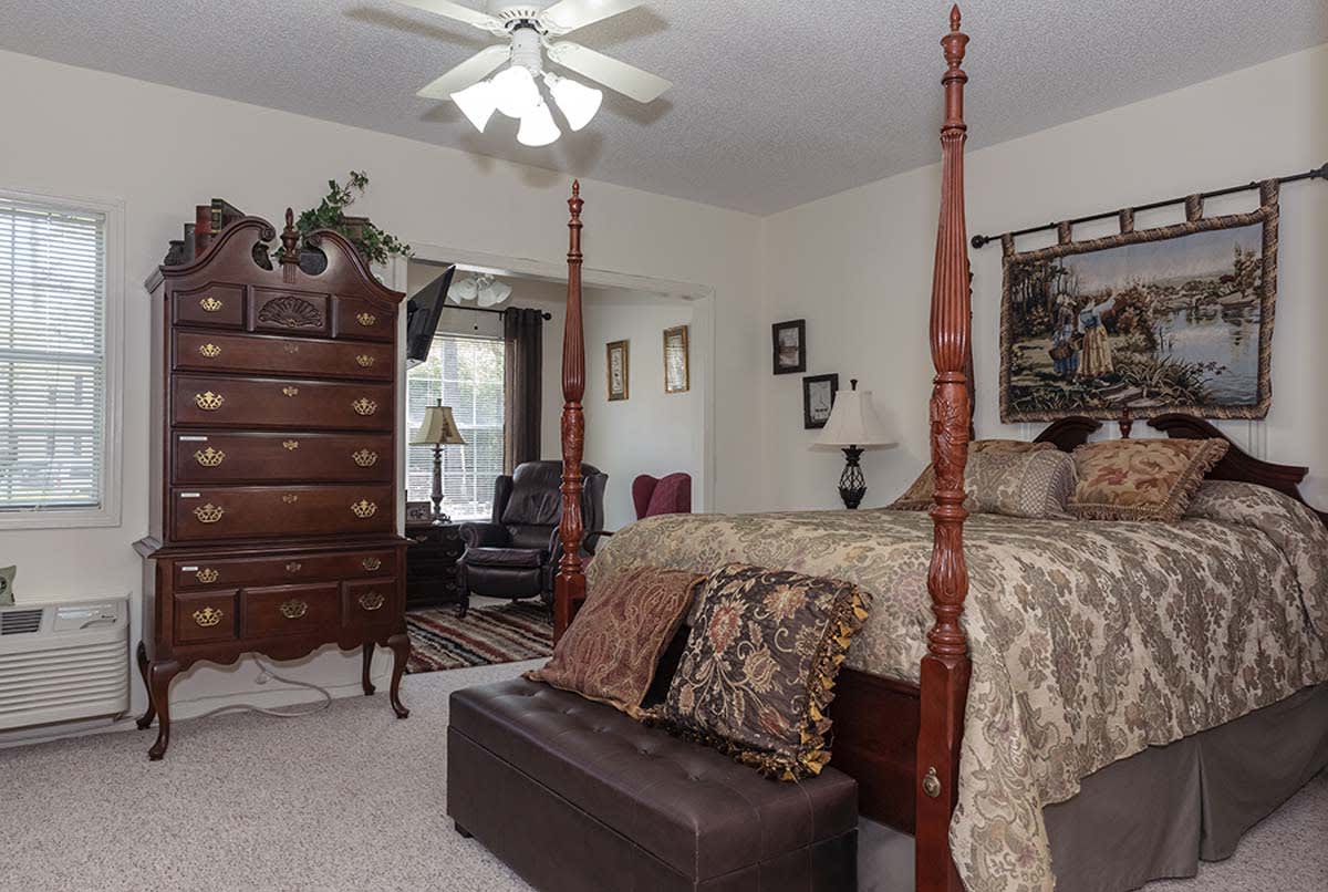 A cozy bedroom featuring a four-poster bed, a wooden dresser, and elegant decor.