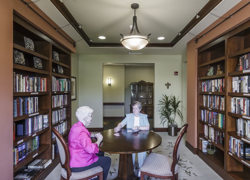 Two people sitting at a table in a library, engaged in conversation.