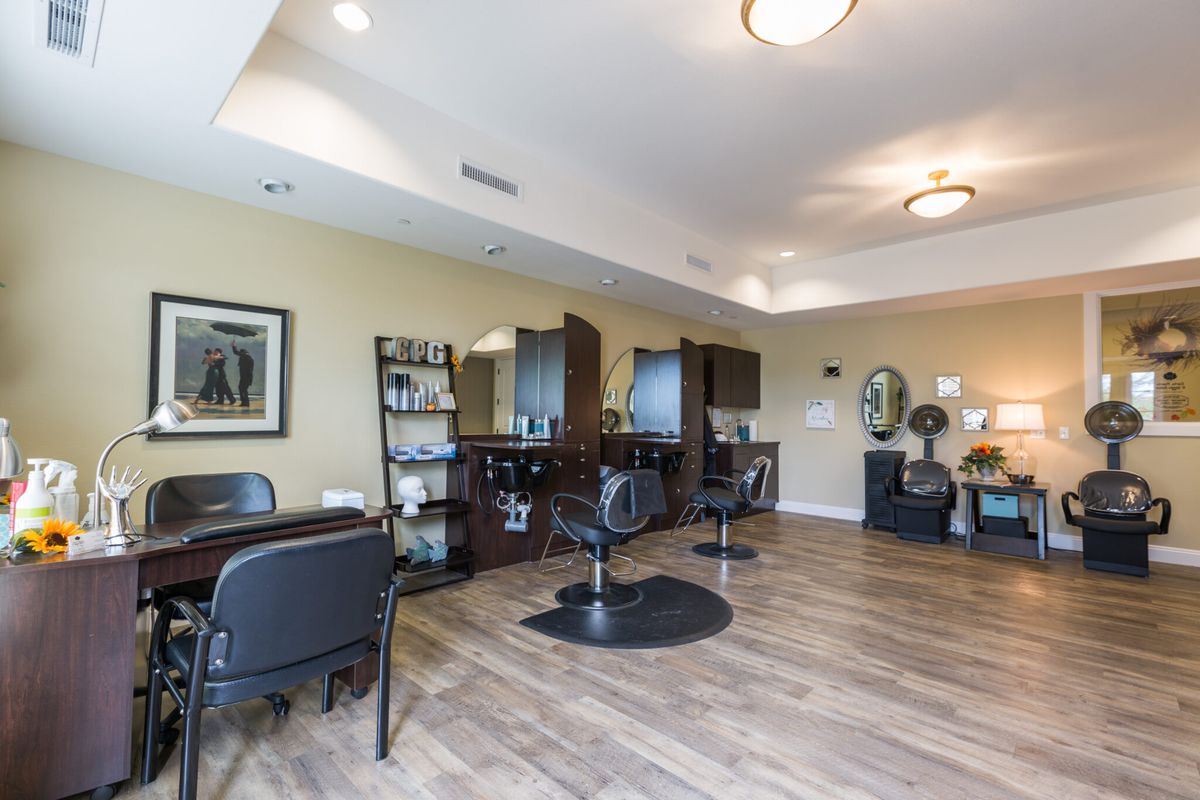 A well-organized hair salon with comfortable chairs and mirrors lining the wall.