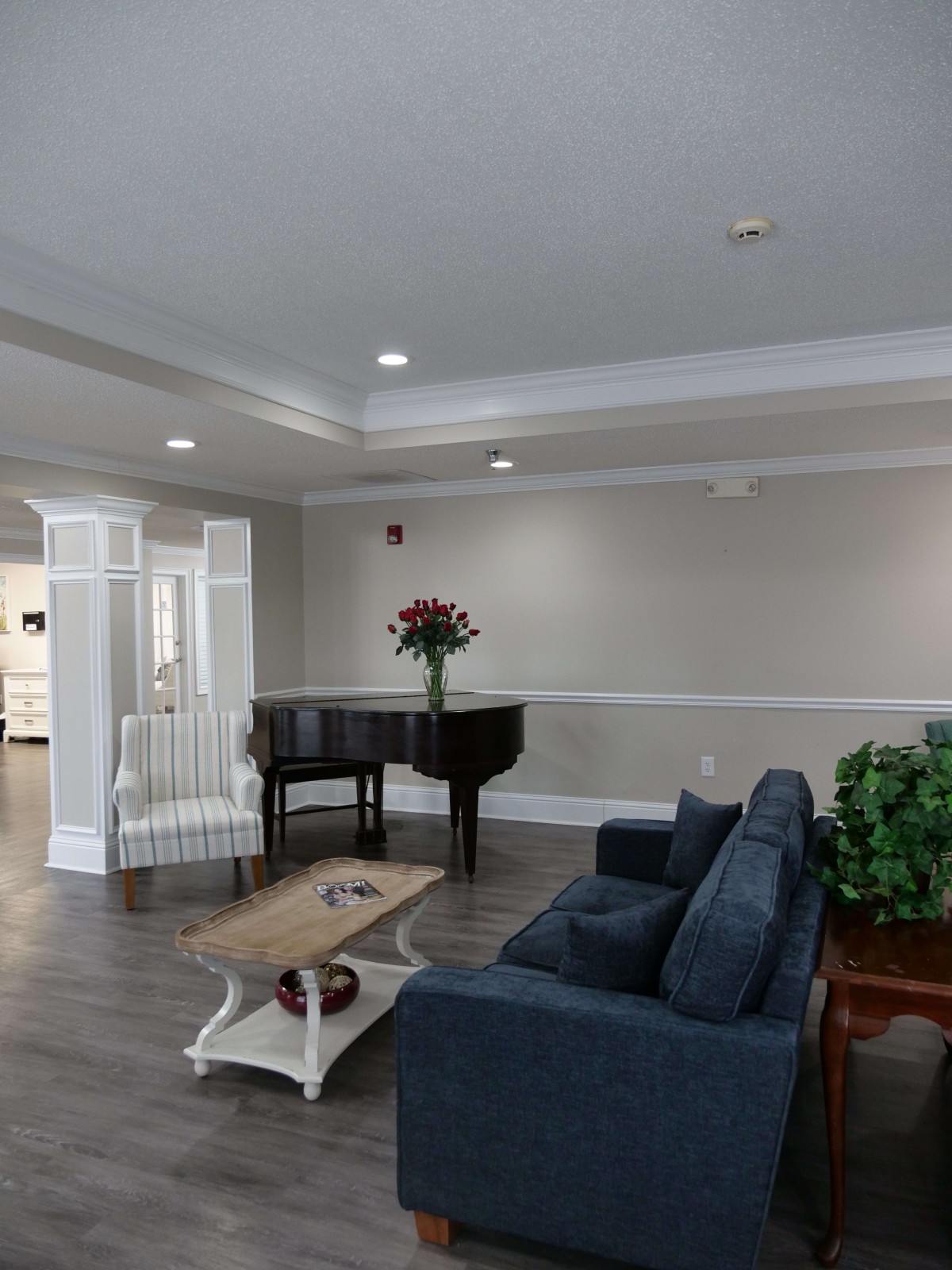 A cozy lobby area featuring a grand piano, seating arrangement, and decorative plants.