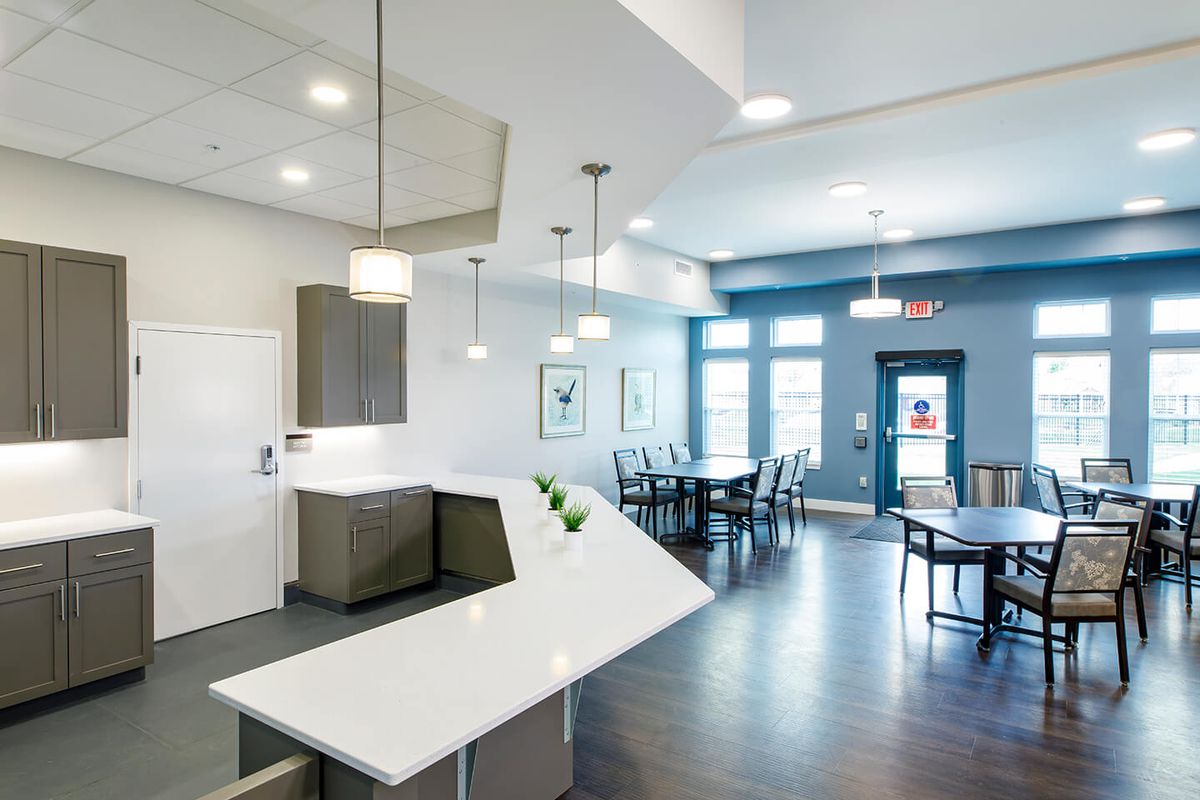 A modern open-plan kitchen and dining area with sleek white countertops and pendant lighting.