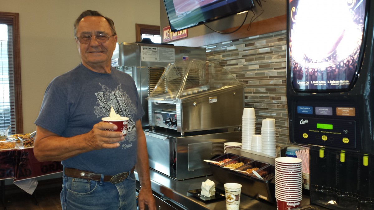 A man enjoys a cup of ice cream indoors.