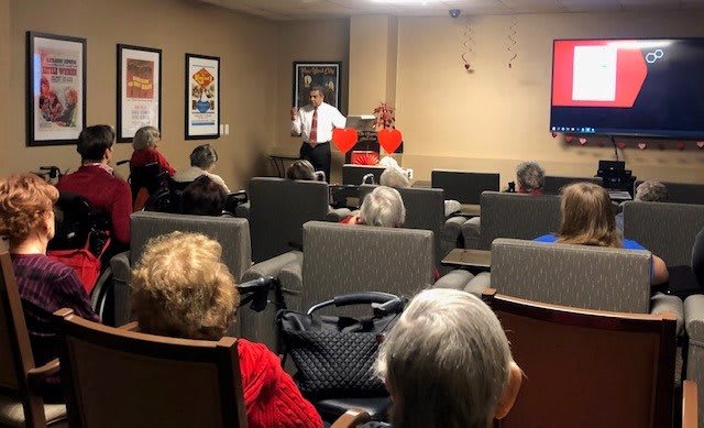 A speaker is presenting to an audience seated indoors.