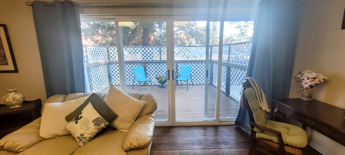 A cozy living room with a sliding glass door leading to a deck with outdoor seating.