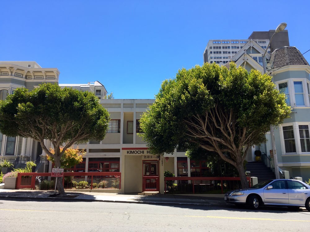 A street view with trees, cars, and buildings on a sunny day.