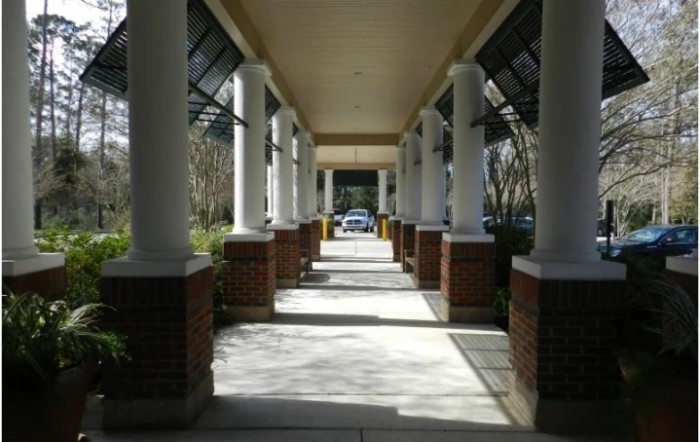 A sunlit corridor with columns casting shadows along the walkway.