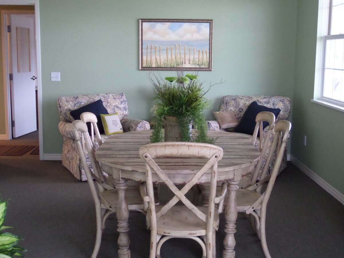 A cozy dining area with a round wooden table, cushioned chairs, and stylish decor in soft colors.