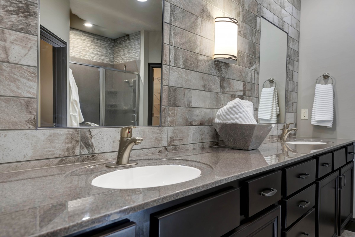 A modern bathroom with a sleek vanity and mirror, featuring elegant lighting and a stone countertop.