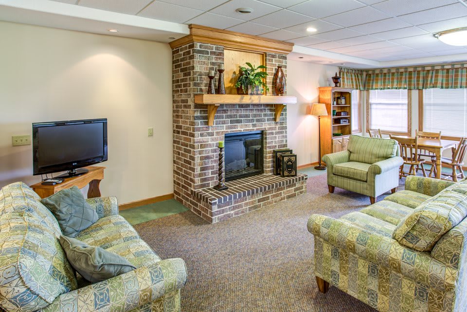 A cozy living room featuring a brick fireplace, comfortable sofas, and a television.